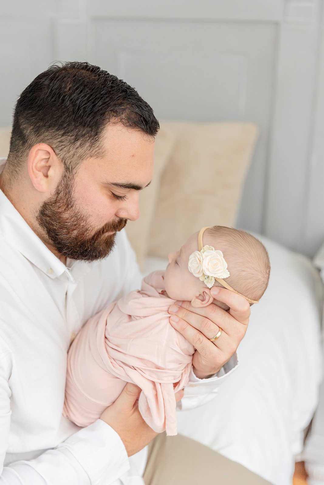 A new dad smiles down at the sleeping newborn baby girl in his hands thanks to a baby sleep consultant CT
