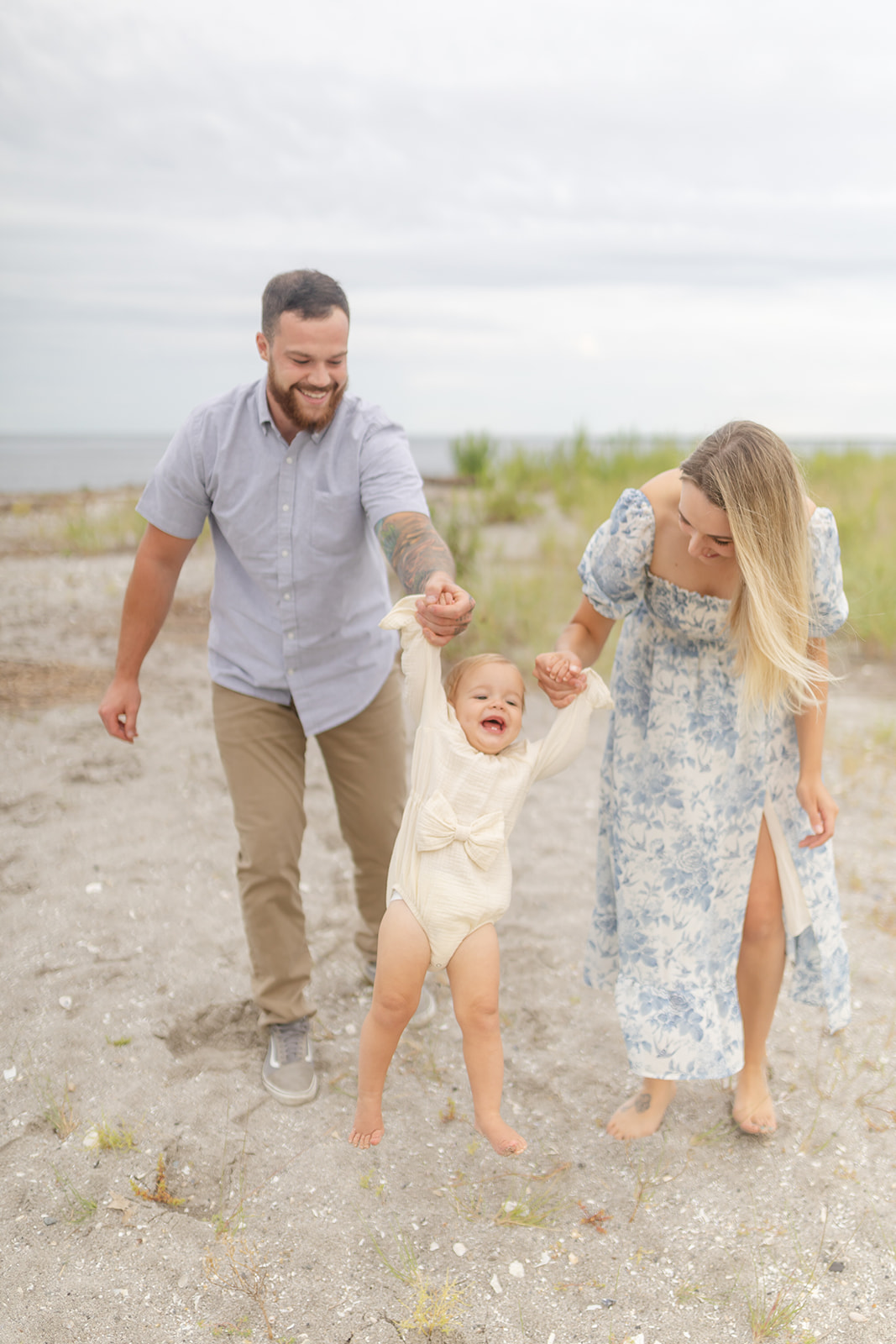 Young parents play with their toddler daughter on a beach after visiting Groove Westport