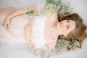 maternity photograph of a mother surrounded by flowers in tulle gown