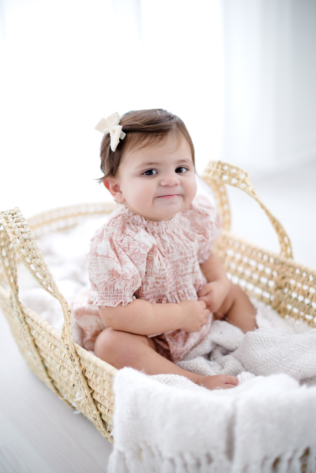 one year old child in a basket wearing pink romper