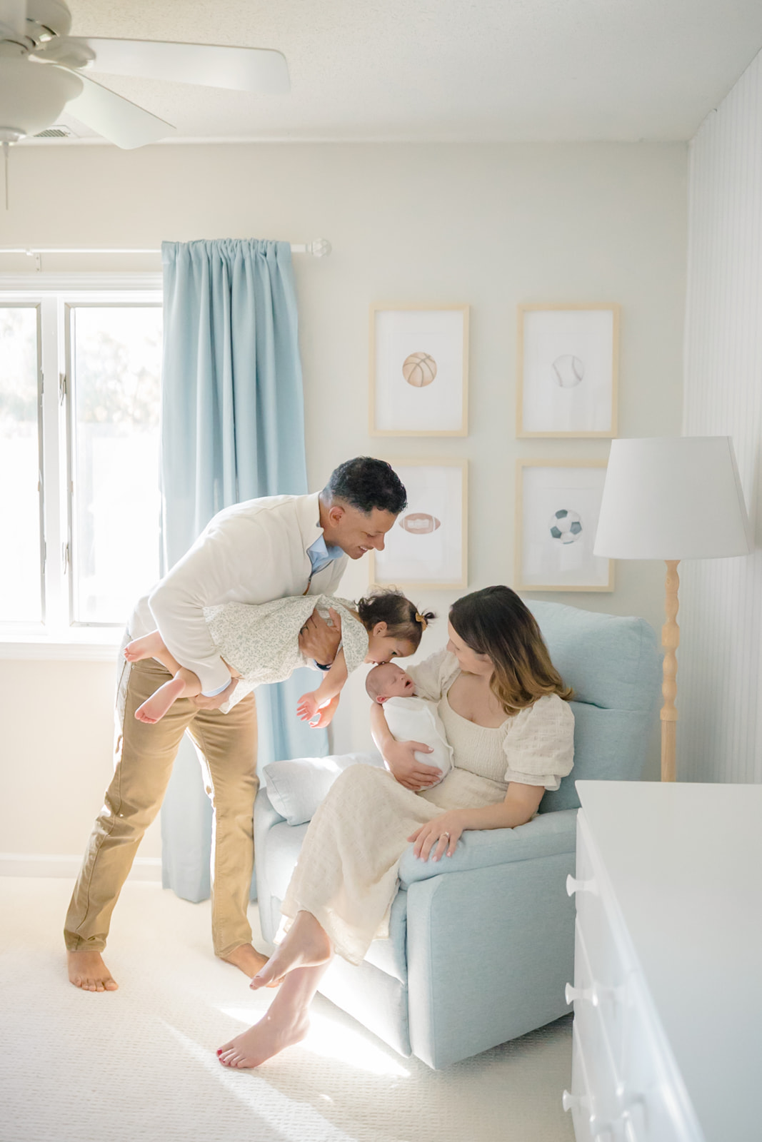 a mom and a dad with a todlder and newborn in a blue and white nursery in branford