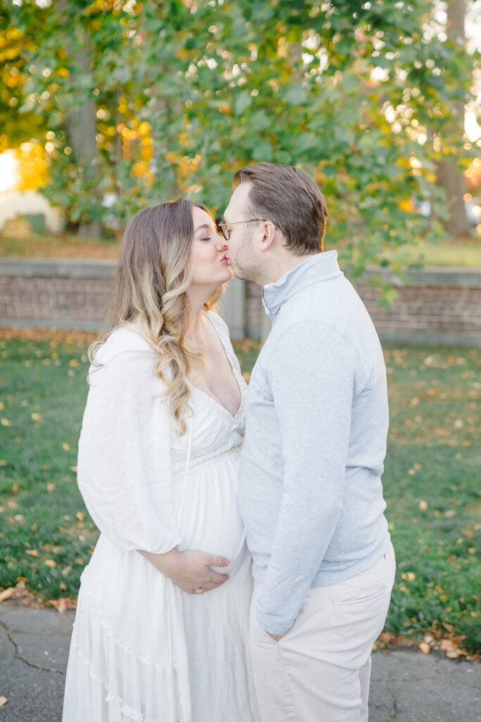 pregnant mom in a white dress holding her belly at new canaan park