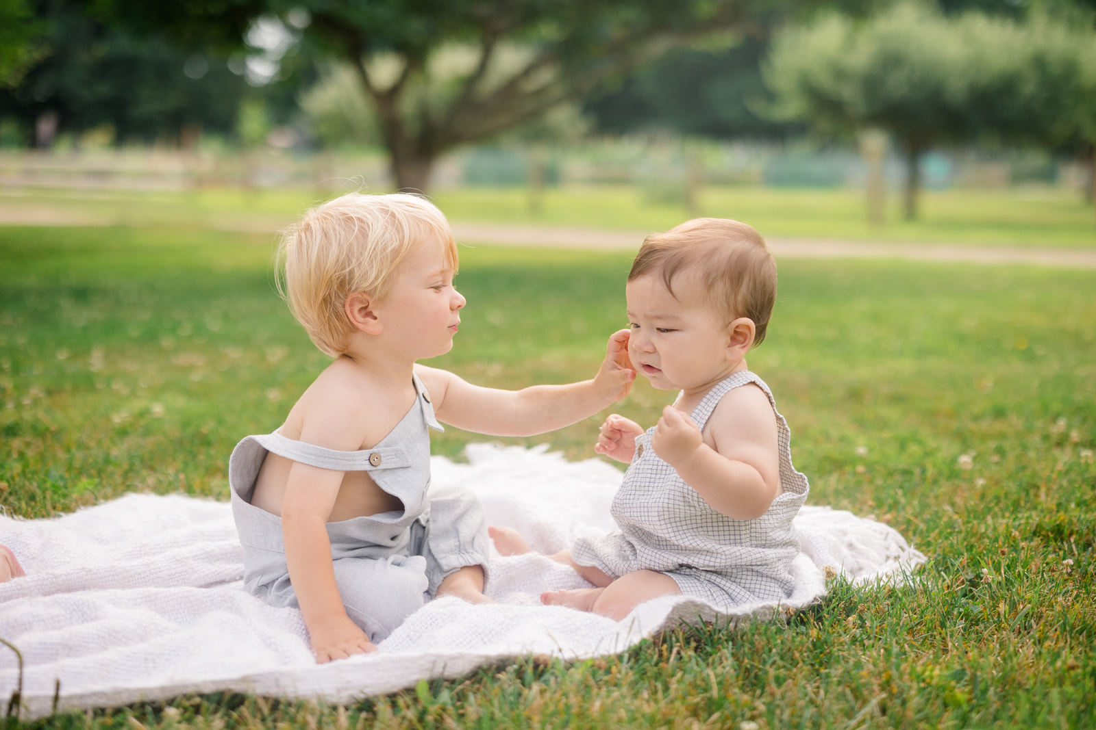 two babies playing on a blanket