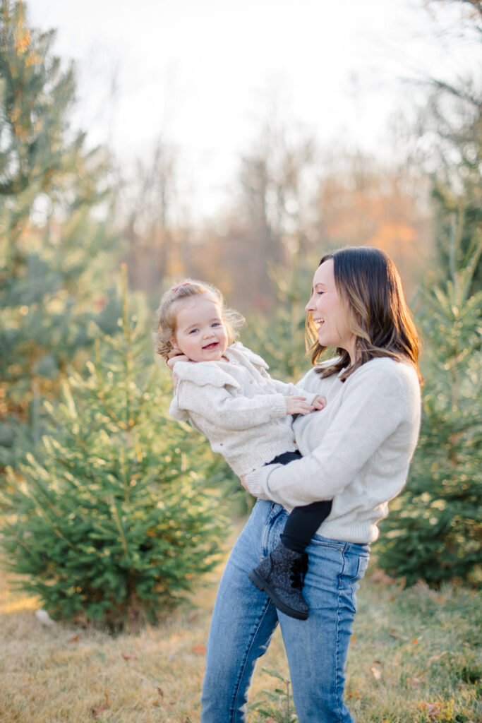 Family posing for festive holiday portraits among evergreen trees