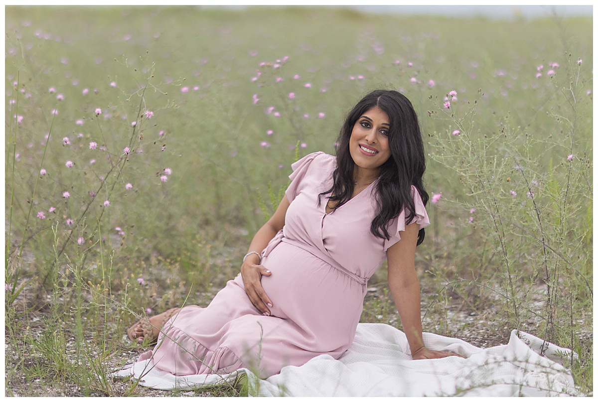 pregnant mom in pink dress sitting in flowers