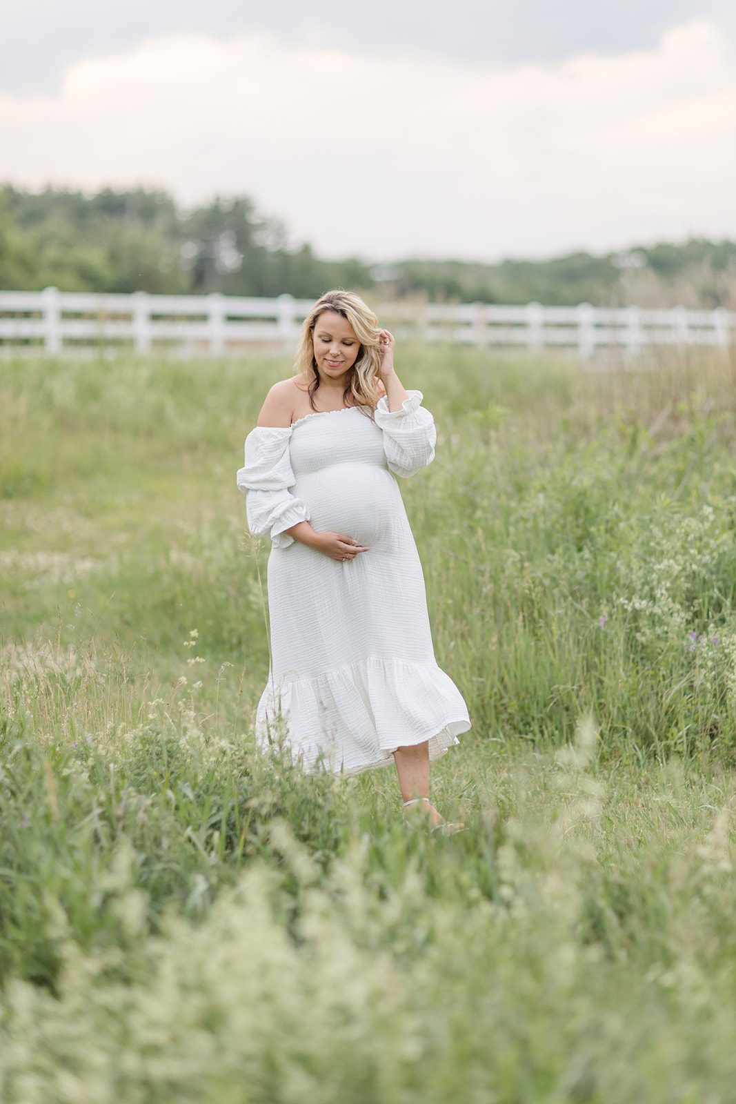 A mom to be pulls her hair back and holds her bump while walking through a park path before visiting Baby shower venues Fairfield CT